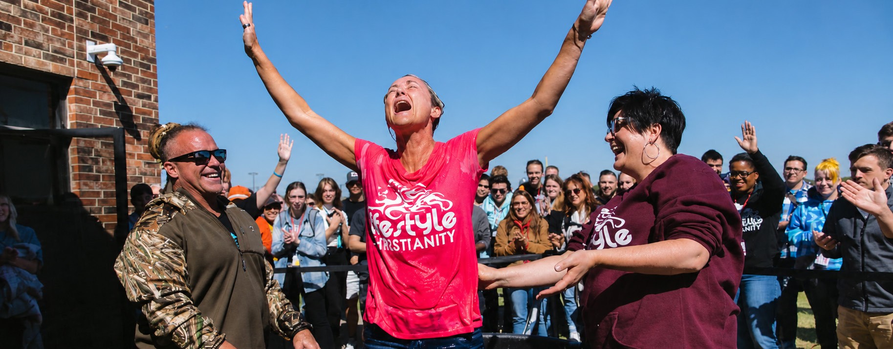 A woman celebrating after her baptism surrounded by a crowd