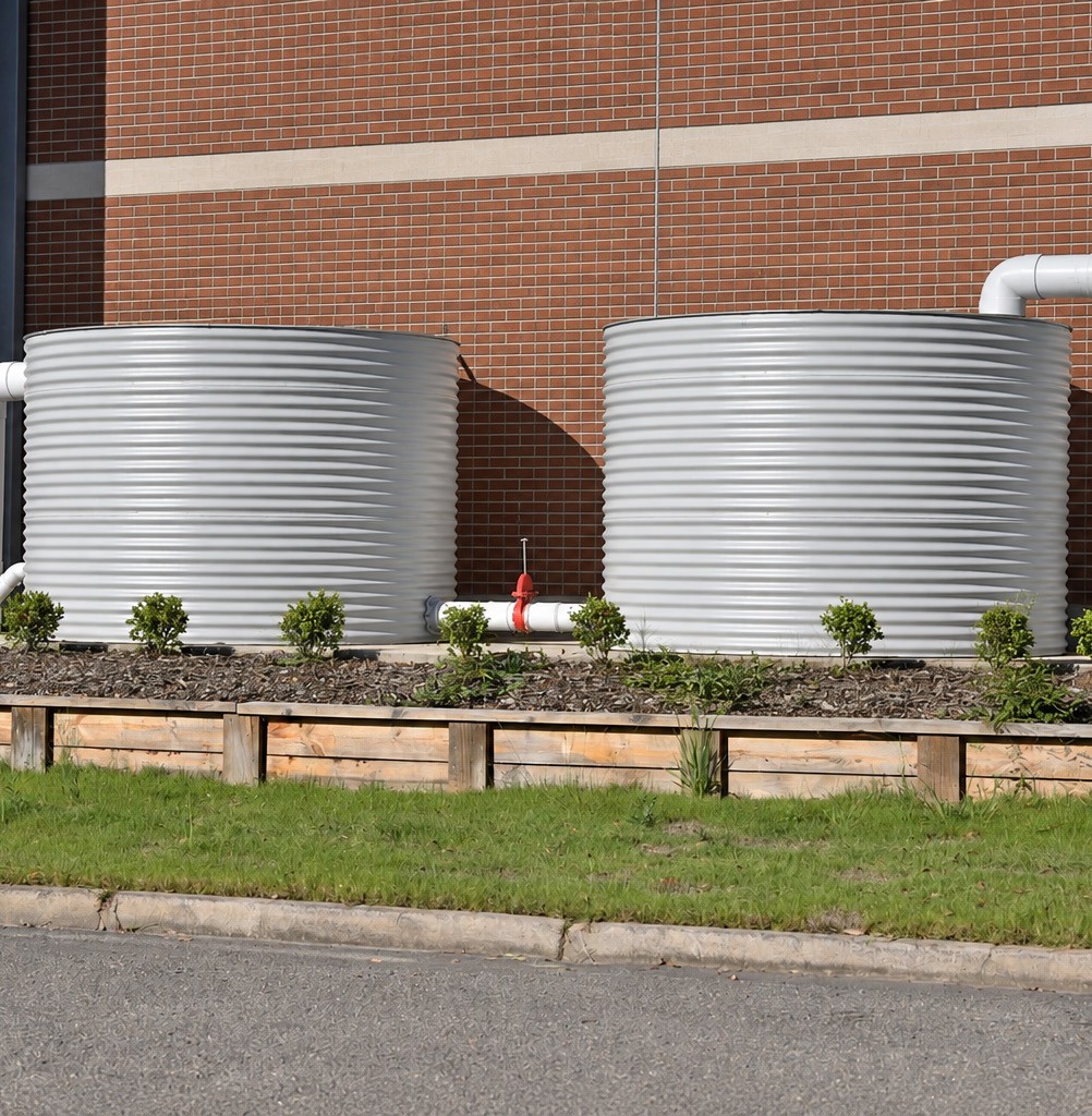 Two 5,000-gallon water storage tanks beside a brick building